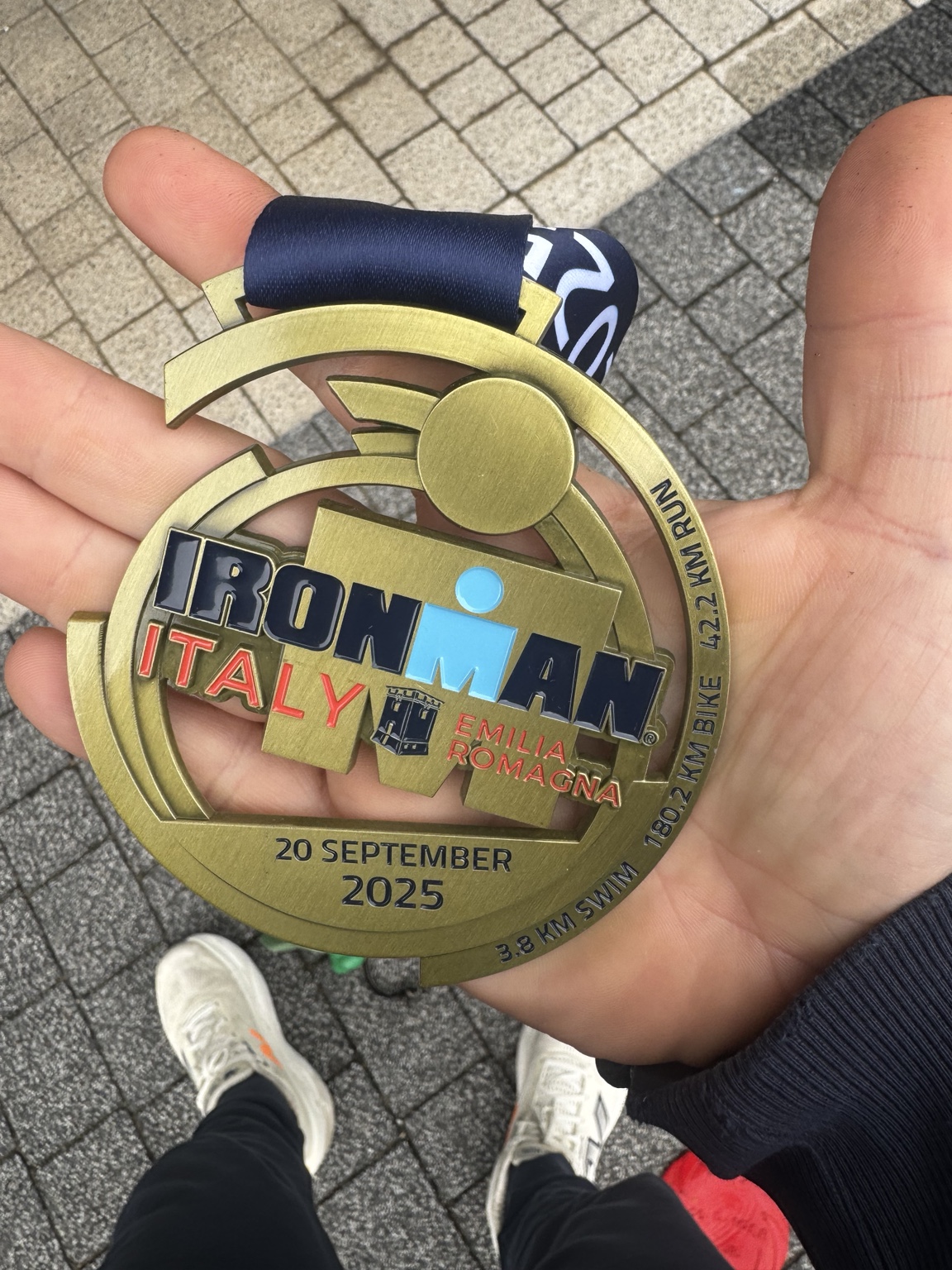 Oryginalne zdjęcie złotego, ażurowego medalu IRONMAN Italy Emilia Romagna z 20 września 2025, trzymanego w dłoni.